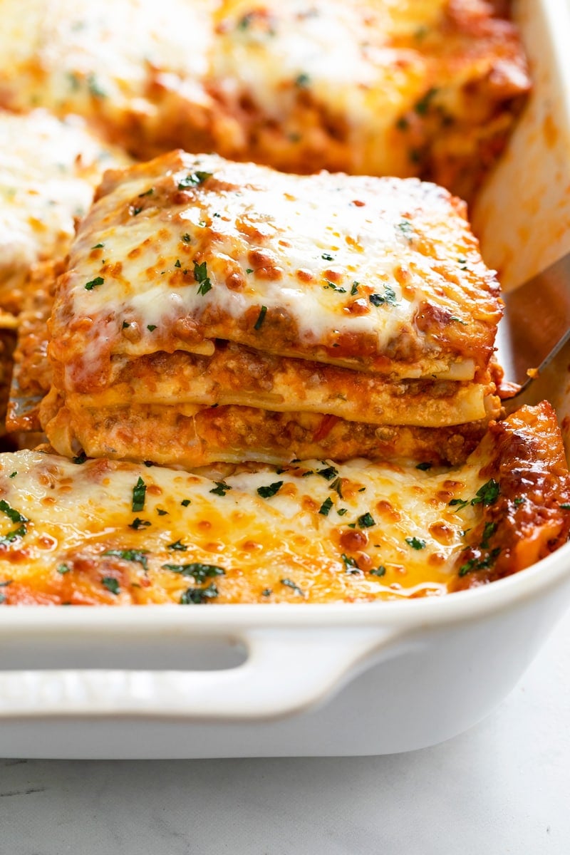 A casserole dish with Lasagna being pulled up with a spatula.